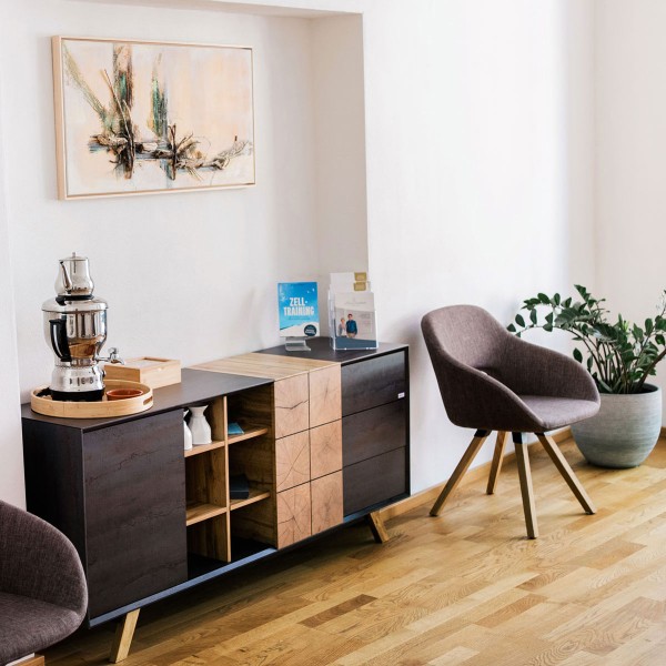 Wartebereich der Praxis Alma Fluente mit Sessel und Teestation