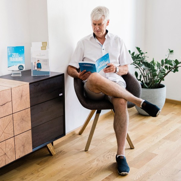 Kundin liest entspannt im Wartebereich der Praxis